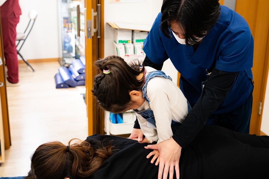 スタッフと一緒に施術を体験する子ども